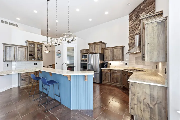 Spacious kitchen featuring a large island with beadboard paneling, granite countertops, and stainless steel appliances