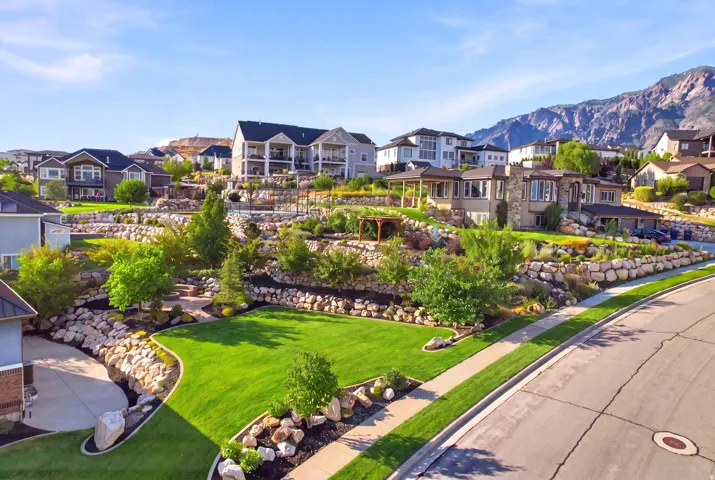 Expansive terraced landscaping featuring rock retaining walls, mature trees, and manicured lawns