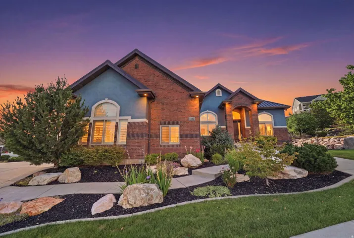 Brick and stucco exterior featuring prominent arch-top windows, an inviting covered entry, and a multi-level roofline