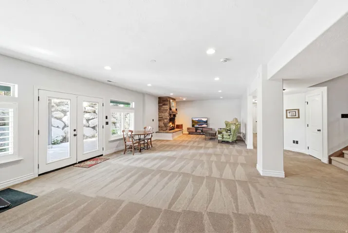 Spacious room featuring broadloom carpeting, a stone-clad fireplace, and recessed lighting