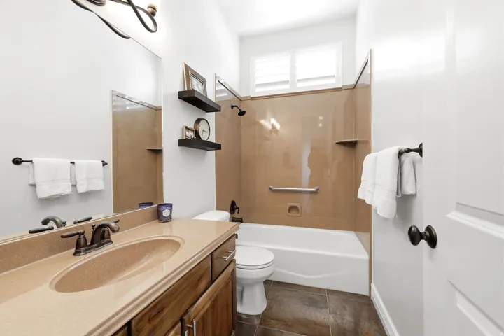 Bathroom vanity featuring a single integrated sink with a bronze-finish faucet, wood cabinetry, and a large wall-mounted mirror