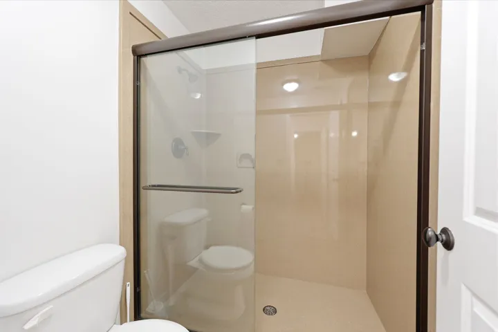Walk-in shower with clear glass enclosure and dark bronze framing