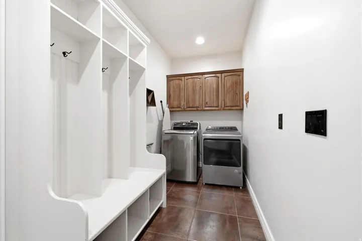 Entry area featuring a built-in white mudroom bench with cubbies and hooks, wood-finish upper cabinetry, and tile flooring