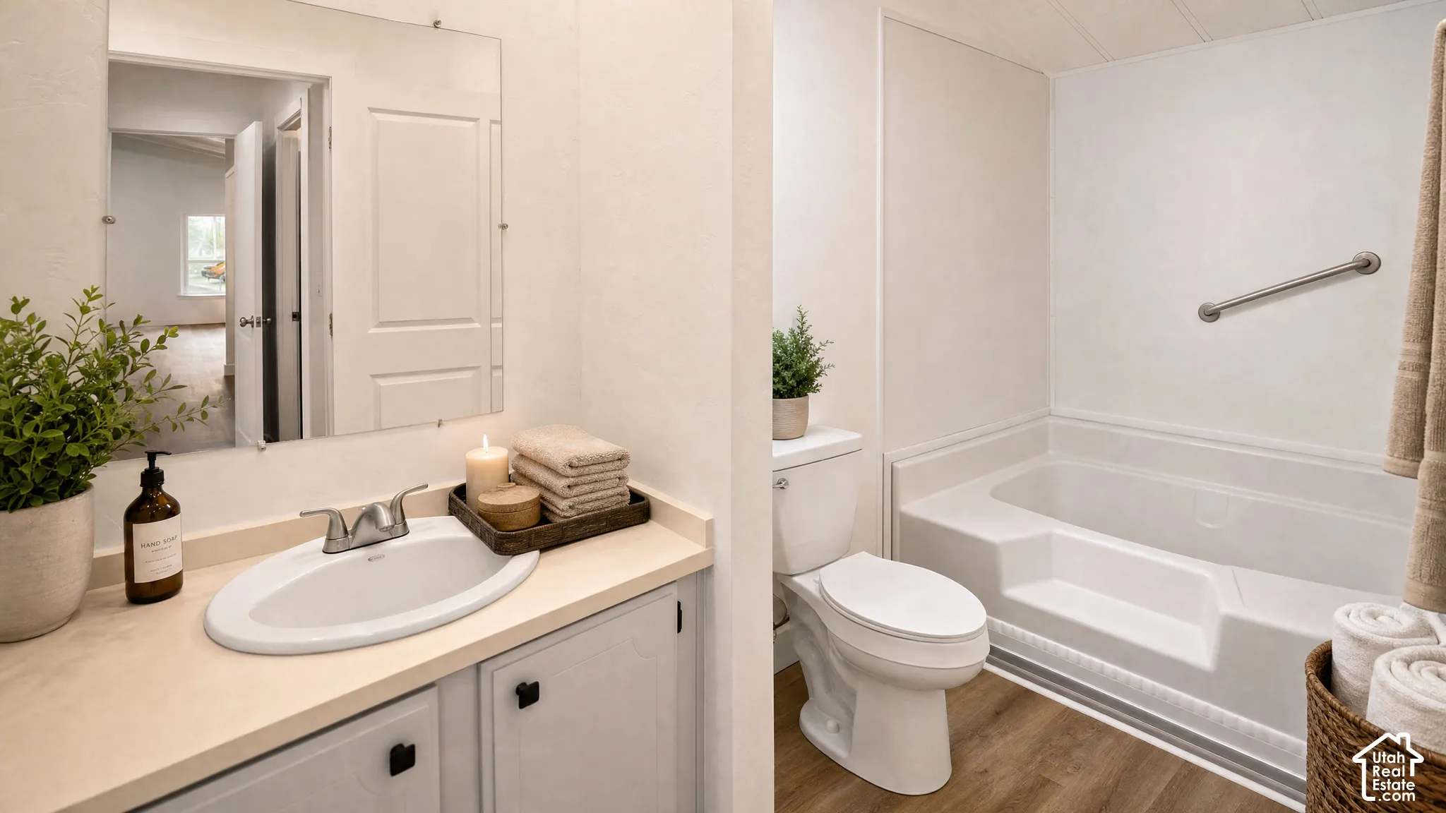 Bathroom featuring a white integrated sink vanity with light cabinetry, a white toilet, and a white bathtub with a grab bar