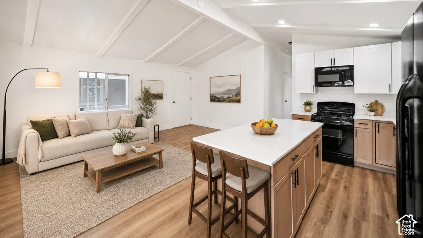 Open-concept living area and kitchen featuring vaulted ceilings, wood-finish flooring, a kitchen island with seating, a white subway tile backsplash, and dark appliances