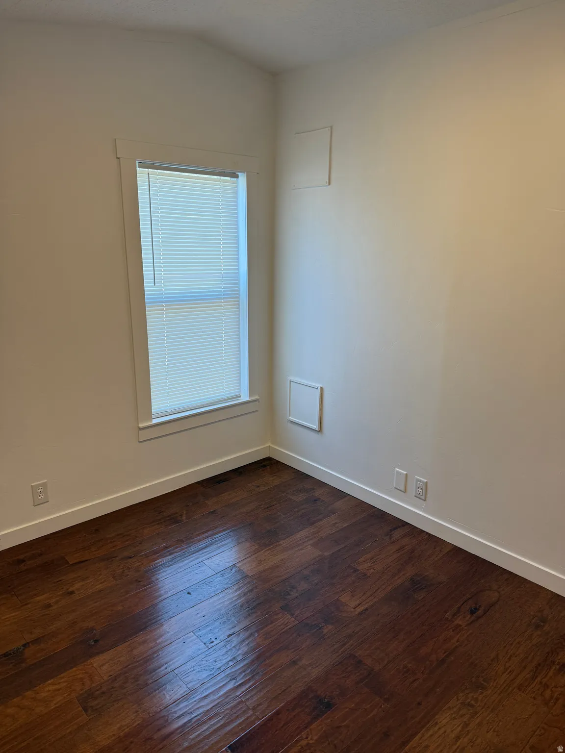 Interiors featuring warm-toned wood-finish flooring, white baseboards, and neutral wall paint