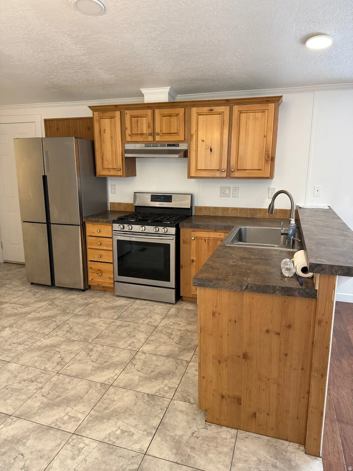 Kitchen featuring wood cabinetry, stainless steel appliances, and a gas range