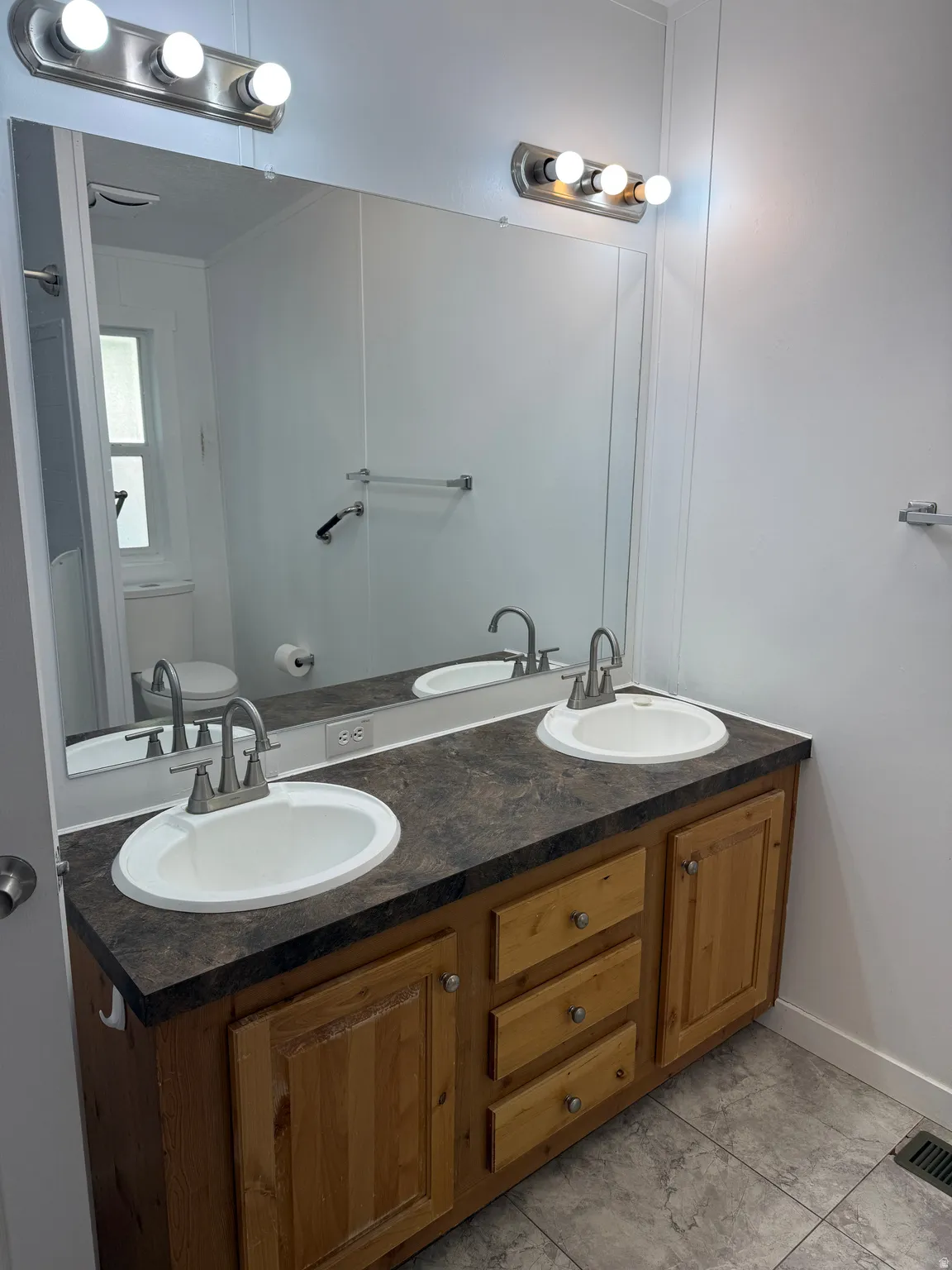 Double vanity with wood-finish cabinetry, two undermount sinks, and brushed nickel faucets