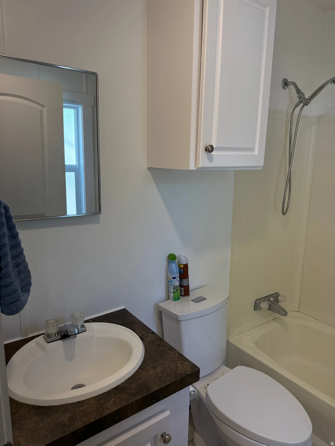 Bathroom featuring a vanity with an integrated sink, a dark patterned countertop, and white cabinetry