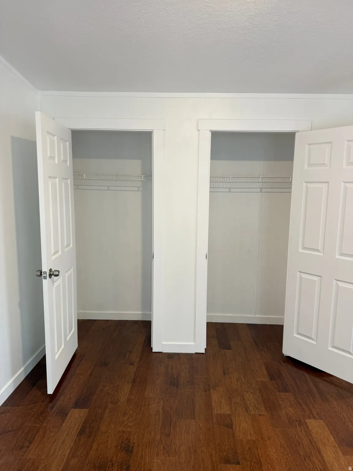 Dual closets featuring paneled doors, wire shelving, and wood-finish flooring