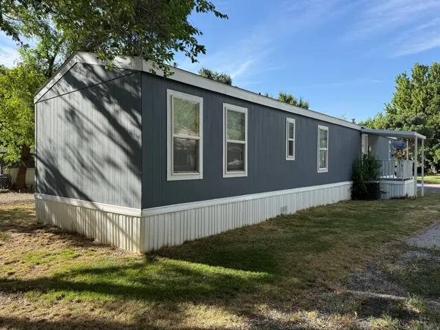 Exterior featuring vertical panel siding, multiple windows, and a covered porch entry