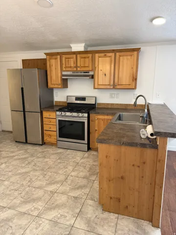 Kitchen featuring wood cabinetry, stainless steel appliances, and a gas range
