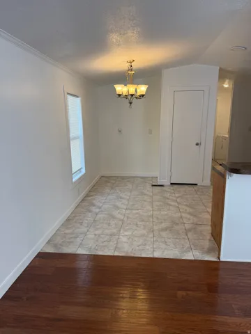 Dining area featuring a bronze-finish chandelier, tile flooring, and a window with blinds