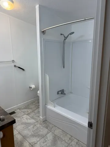 White acrylic tub and shower combination with a curved shower rod