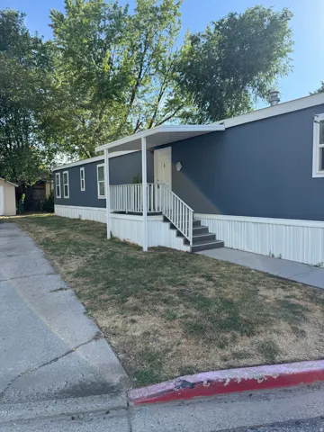 Dark blue siding home with white trim, featuring an exterior staircase with white railings, a covered entryway, and a small front yard area