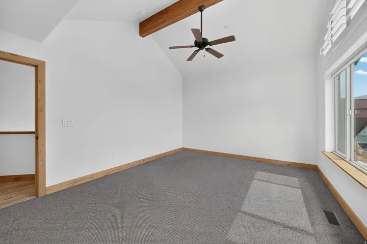Vaulted ceiling with an exposed wood beam, integrated ceiling fan, and recessed lighting