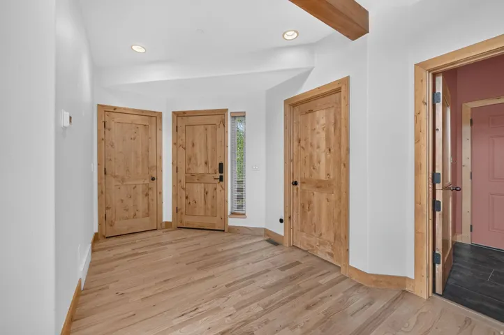 Entryway featuring light wood-finish flooring, recessed lighting, and natural wood doors with black hardware