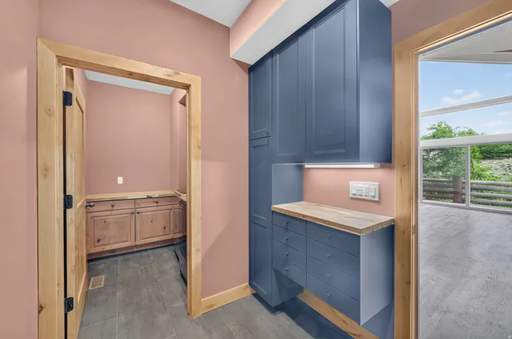 Built-in blue cabinetry with wood-finish countertops, under-cabinet lighting, and integrated electrical outlets