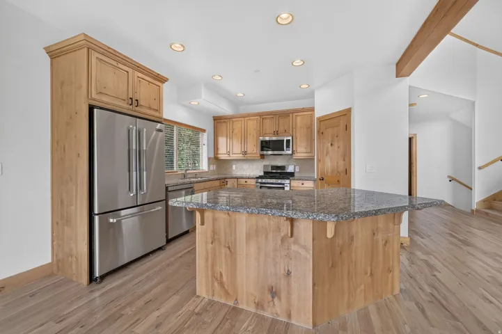 Contemporary kitchen featuring stainless steel appliances, light wood-finish cabinetry, a large center island with a granite countertop, and recessed lighting