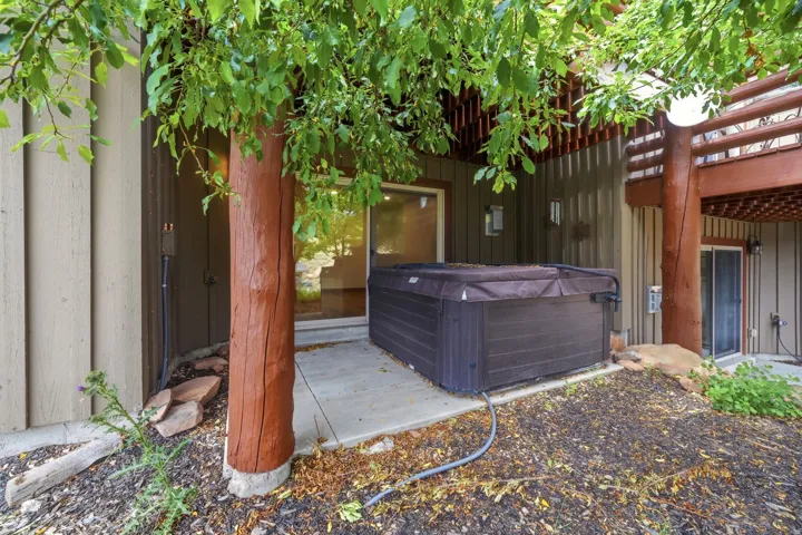 Outdoor hot tub on a concrete patio with surrounding natural landscaping