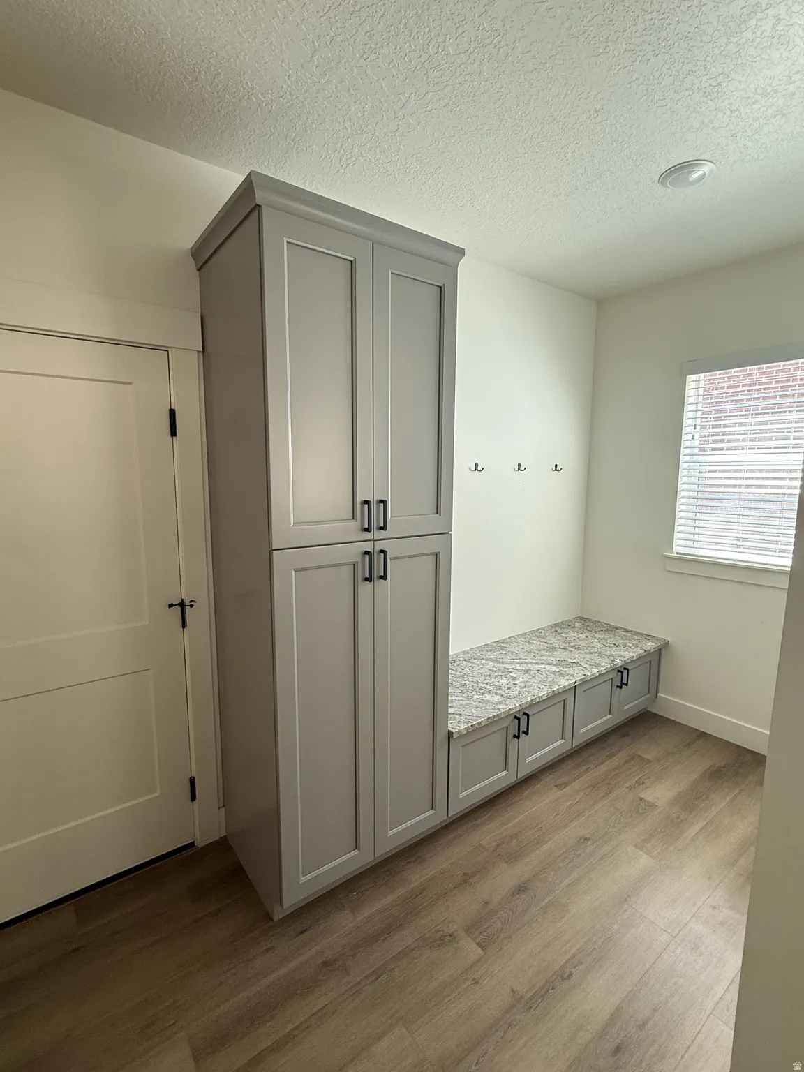 Built-in gray cabinetry with black hardware, complementing a gray speckled countertop and wood-finish flooring