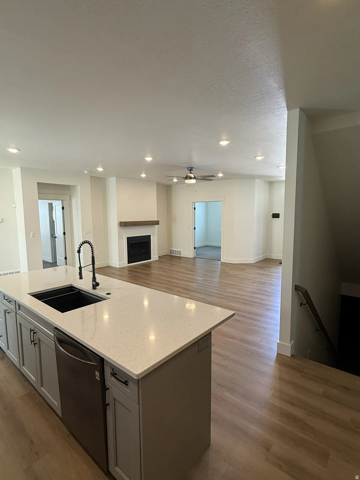 Kitchen island with integrated sink, stainless steel dishwasher, and light-toned solid surface countertop