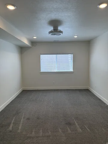 Spacious room featuring gray carpeting, white walls, and bright recessed lighting