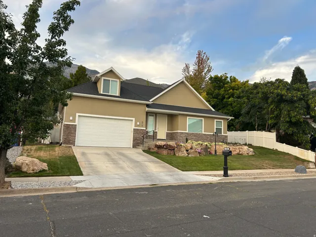 Split-level residence featuring a light tan stucco and stone veneer exterior
