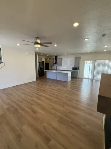 Spacious open-concept living area featuring wood-finish flooring, recessed lighting, and a ceiling fan