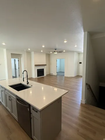 Kitchen island with integrated sink, stainless steel dishwasher, and light-toned solid surface countertop