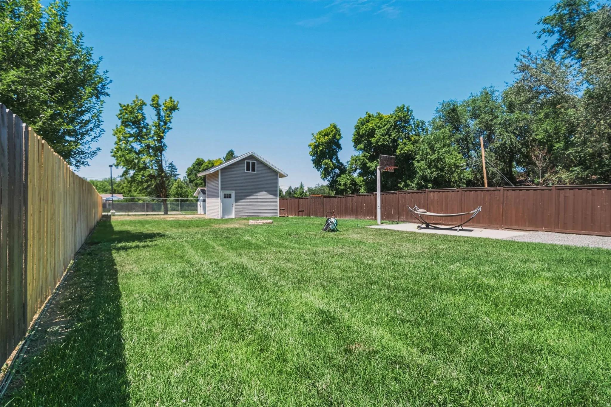Expansive green lawn with a detached two-story accessory building featuring gray siding and white trim