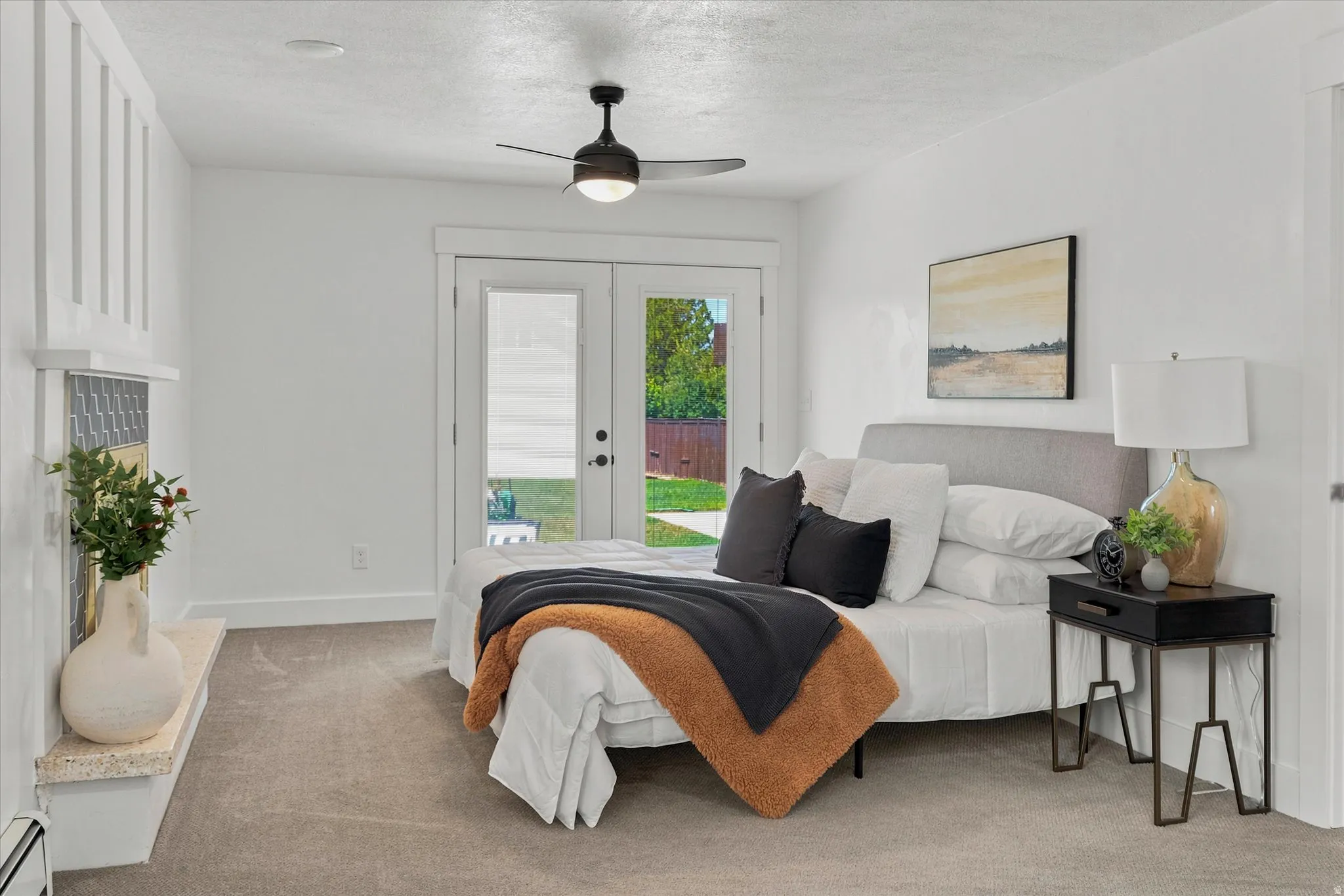 Primary bedroom featuring light gray carpeting, a built-in fireplace with a decorative mantel, and French doors providing outdoor access