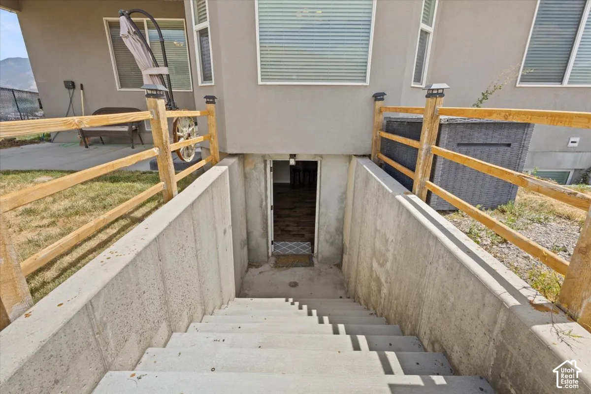 Concrete stairway descending to a ground-level entry, framed by a wooden split-rail fence with post-cap lighting