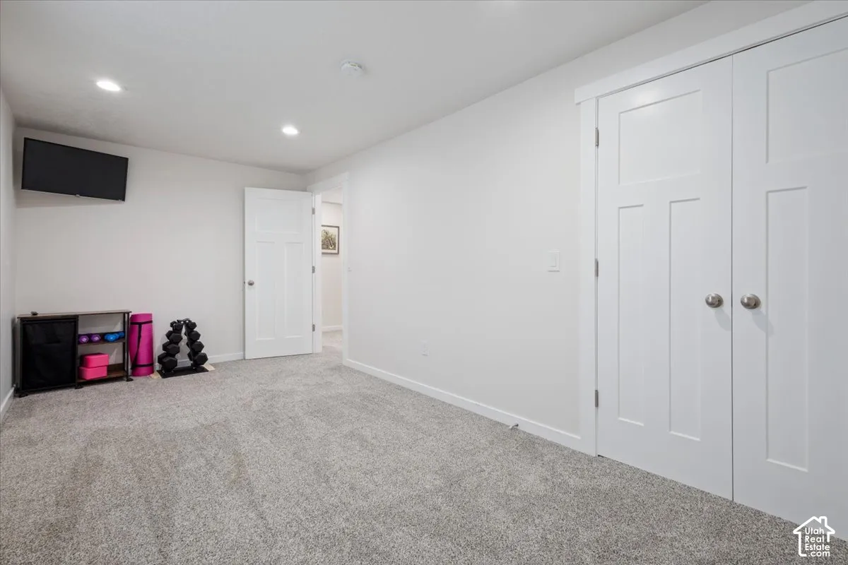 Carpeted room featuring recessed lighting, a paneled interior door, and double paneled closet doors with brushed nickel hardware
