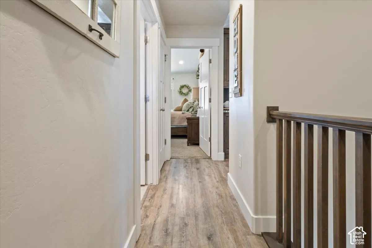 Hallway featuring wood-finish flooring, white walls, and white trim