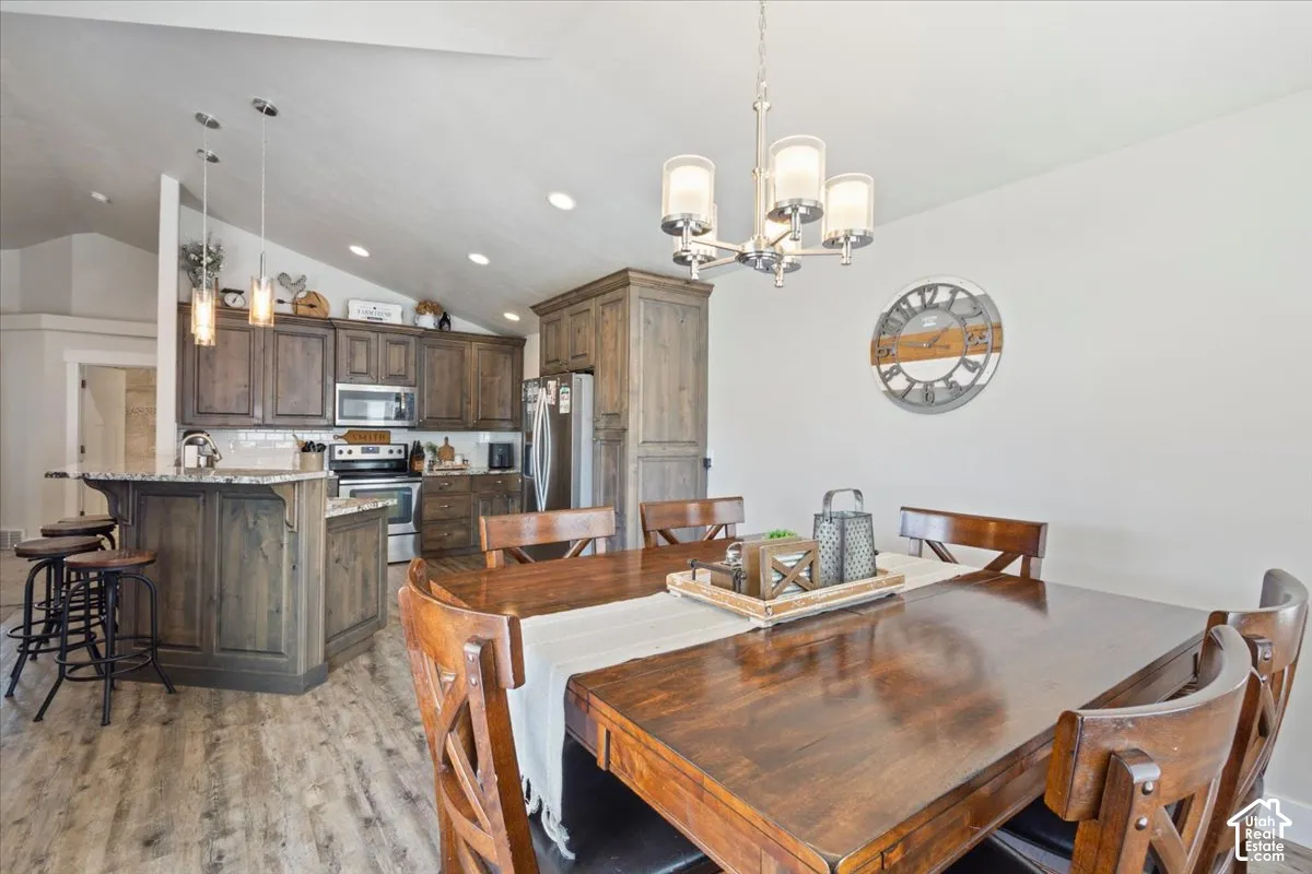 Dining area featuring a contemporary chandelier, wood-finish flooring, and an open concept layout