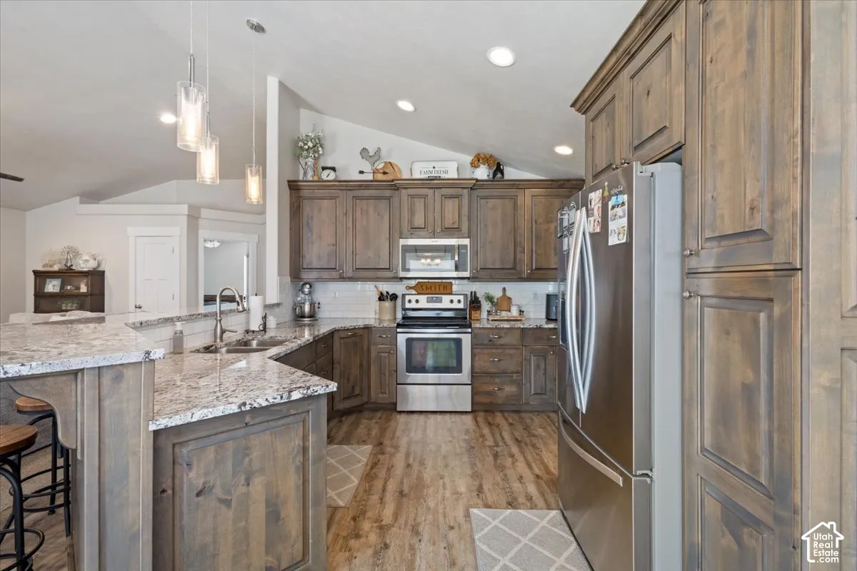 Modern kitchen featuring wood-finish cabinetry, stainless steel appliances, and a light-toned countertop