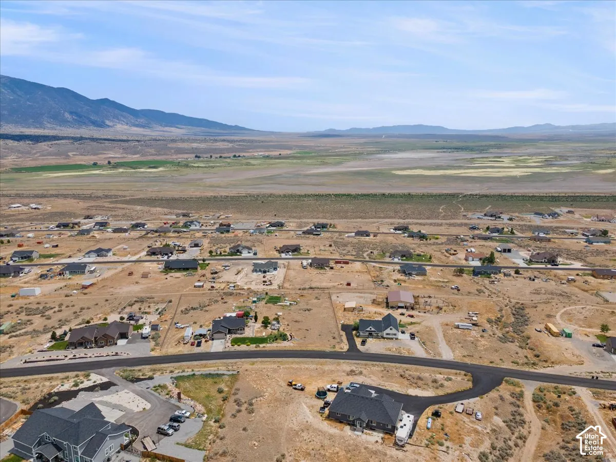 Residential community featuring a variety of single-story and multi-story homes, paved roads, and undeveloped land parcels