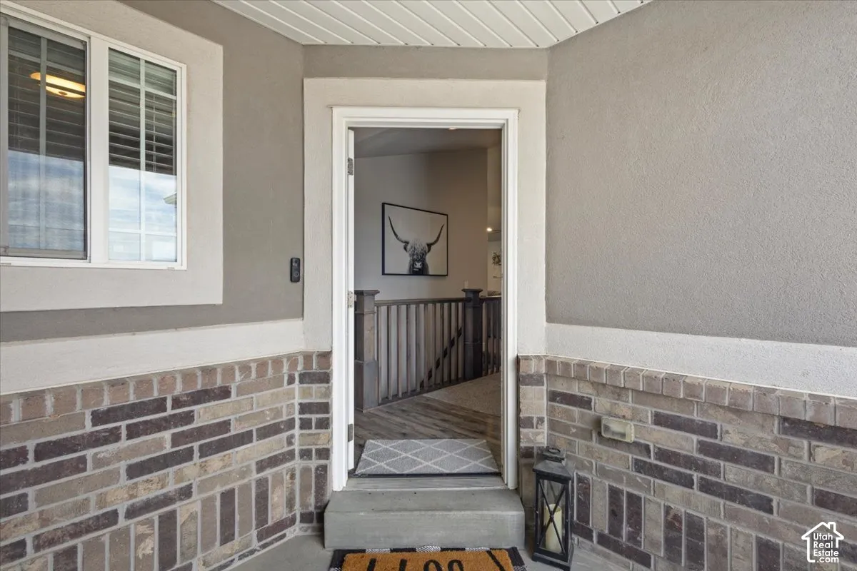 Entryway featuring mixed-material facade with brick and stucco, white trim, and white window frames