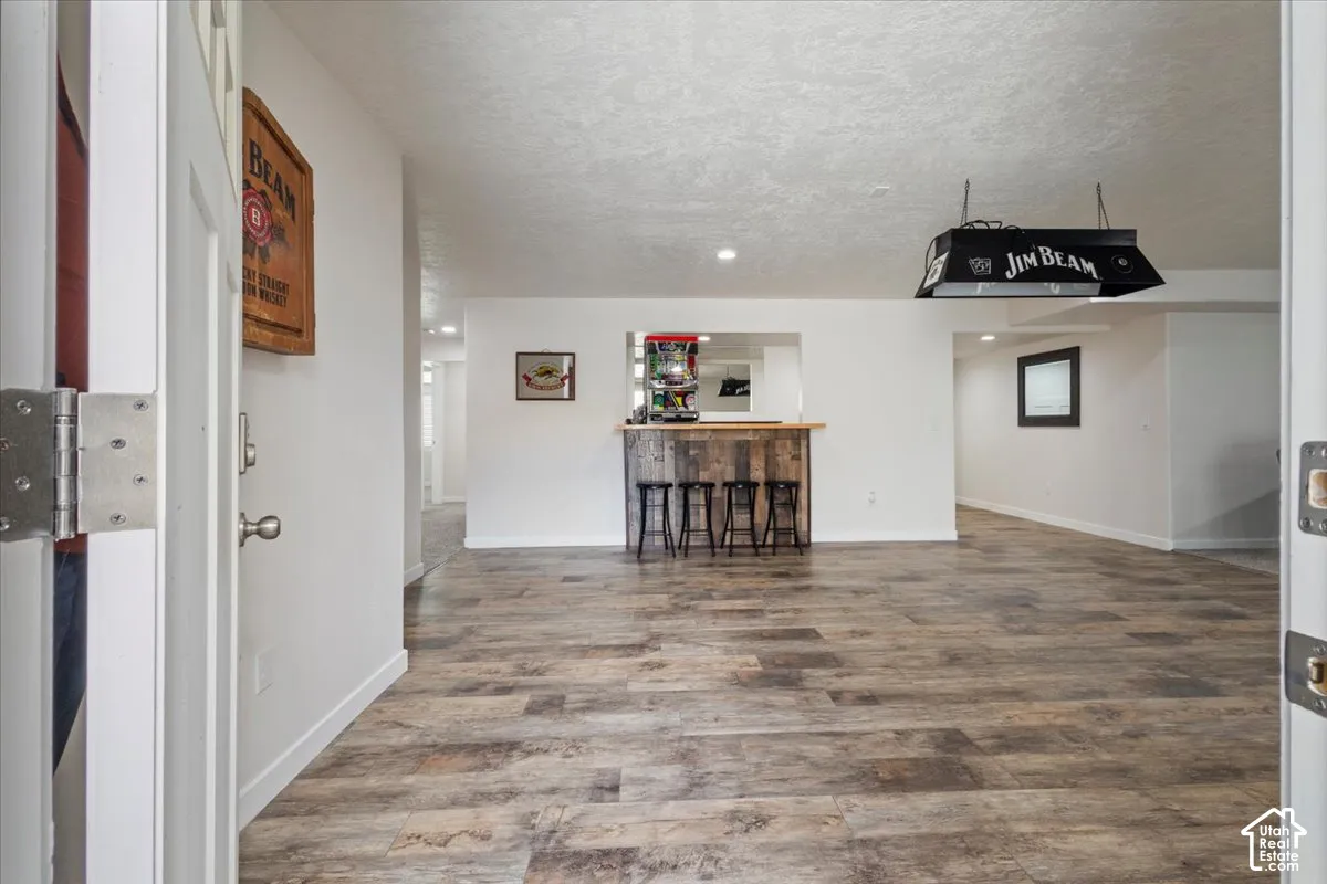 Spacious room featuring wood-finish flooring, white walls, and recessed lighting