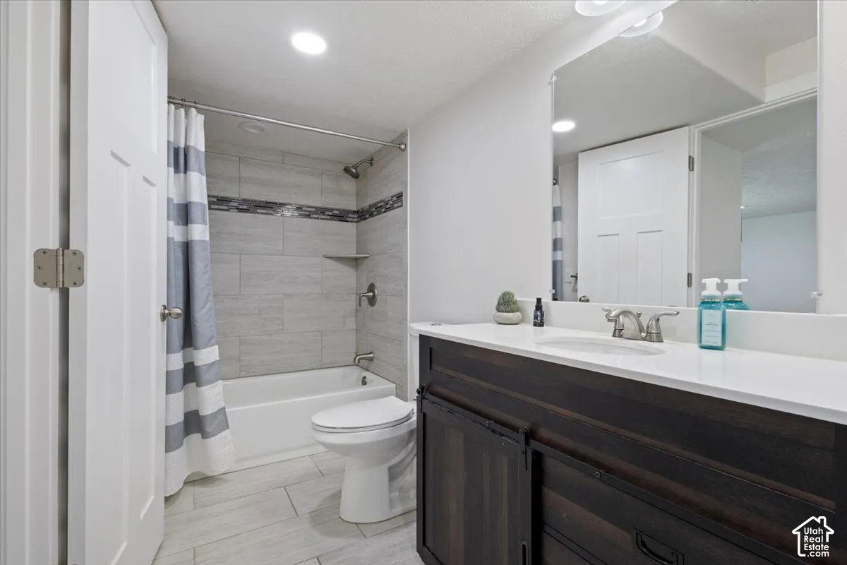 Bathroom featuring a dark wood-finish vanity with a white countertop and undermount sink, a large wall-mounted mirror, and tile flooring