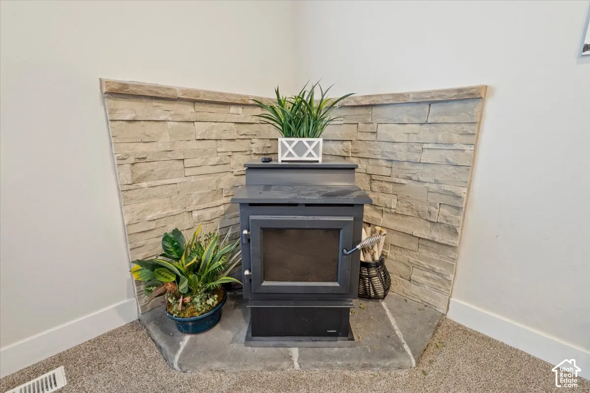 Corner wood-burning stove featuring a glass-front door, set against a stacked stone accent wall