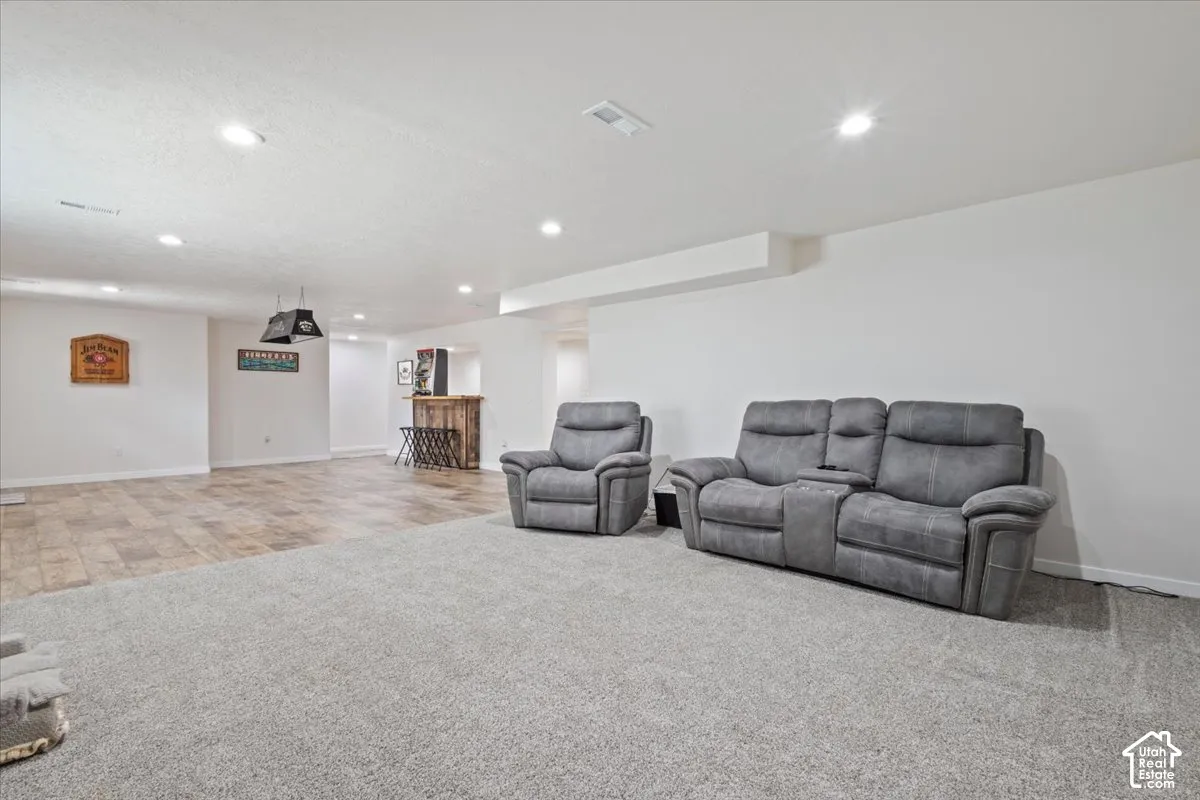 Lower level featuring recessed lighting and a combination of light gray carpeting and wood-finish flooring