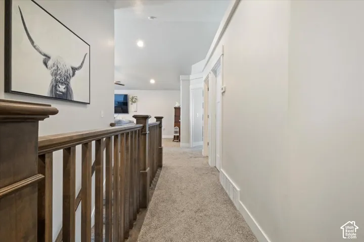 Upper-level hallway with wood-finish railing and carpeted flooring