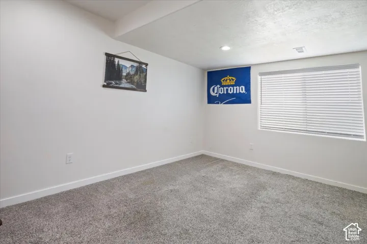 Carpeted room featuring white walls, a recessed ceiling light, and a window with horizontal blinds