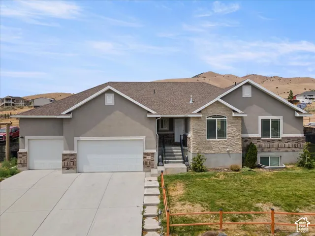 Contemporary stucco and stone exterior featuring a two-car garage, an additional single-car garage, and a concrete driveway