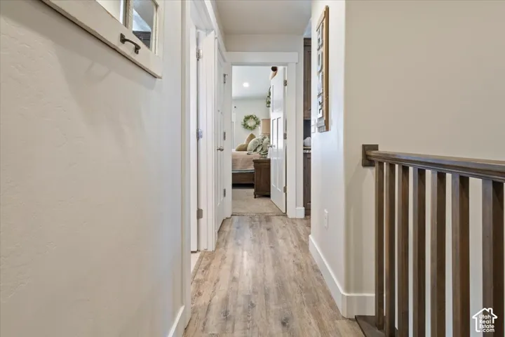 Hallway featuring wood-finish flooring, white walls, and white trim