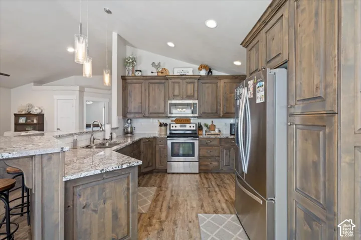 Modern kitchen featuring wood-finish cabinetry, stainless steel appliances, and a light-toned countertop