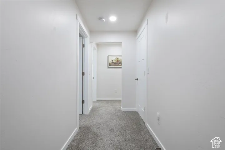 Hallway featuring light gray carpeting, white painted walls, and white trim