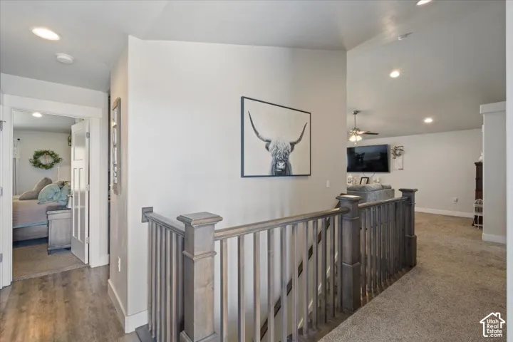 Upper-level hallway with wood-finish flooring, recessed lighting, and a stained wood-finish staircase railing